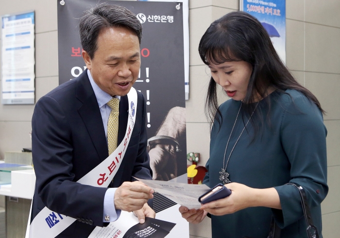 신한은행이 27일 서울 중구 소재 본점 영업부에서 진행한 첫번째 ‘보이스피싱 피해 근절 캠페인’에서 진옥동 은행장(왼쪽)이 고객에게 피해예방 안내장을 배부하고 내용을 설명하는 모습. 사진=신한은행 제공