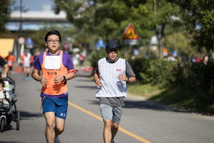 시각장애인 마라토너와 달리기 도우미인 OCI 직원이 함께 10km를 완주하고 있다. 사진=OCI 제공