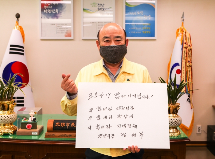 정현복 광양시장이 14일 ‘코로나19 함께 이겨냅시다 힘내라 대한민국, 힘내라 광양시, 힘내라 지역경제’라는 메시지를 직접 손으로 쓴 뒤 들어 올리고 있다.