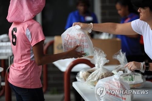 코로나19로 미국의 학교들이 문을 닫은 가운데 지난 3월 한 초등학교에서 교직원들이 학생들에게 음식과 책 등이 들어있는 가방을 나눠주고 있다. 사진=연합뉴스 제공