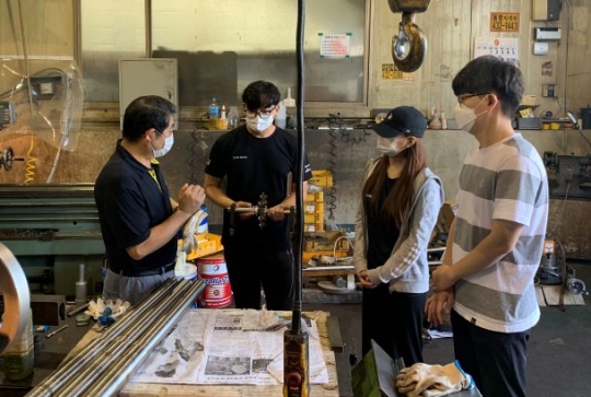 광남정밀 권년택 대표(좌측)가 산기대 김동현·임수영·원용준 학생들이 제작한 부품을 살펴본 뒤 문제점을 자문 해주고 있다.