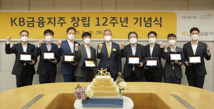 KB금융지주가 29일 오전 서울 여의도동 본점에서 유튜브 비대면 생중계 방식으로 창립 12주년 기념식을 열었다. 이날 기념식에서 윤종규 회장(가운데)이 장기근속 표창을 받은 임직원들과 기념촬영을 하고 있다. 사진=KB금융지주 제공