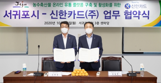 지난 26일 제주 서귀포시청에서 농·수·축산물 온라인 유통 플랫폼 구축을 위한 업무협약을 체결한 문동권 신한카드 경영기획그룹장(오른쪽)과 김태엽 서귀포시장이 기념촬영을 하고 있다. 사진=신한카드